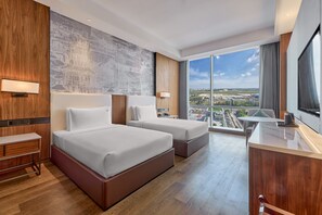 Relax in a spacious room with a large bed, a smaller bed, and a desk area, offering a city view.