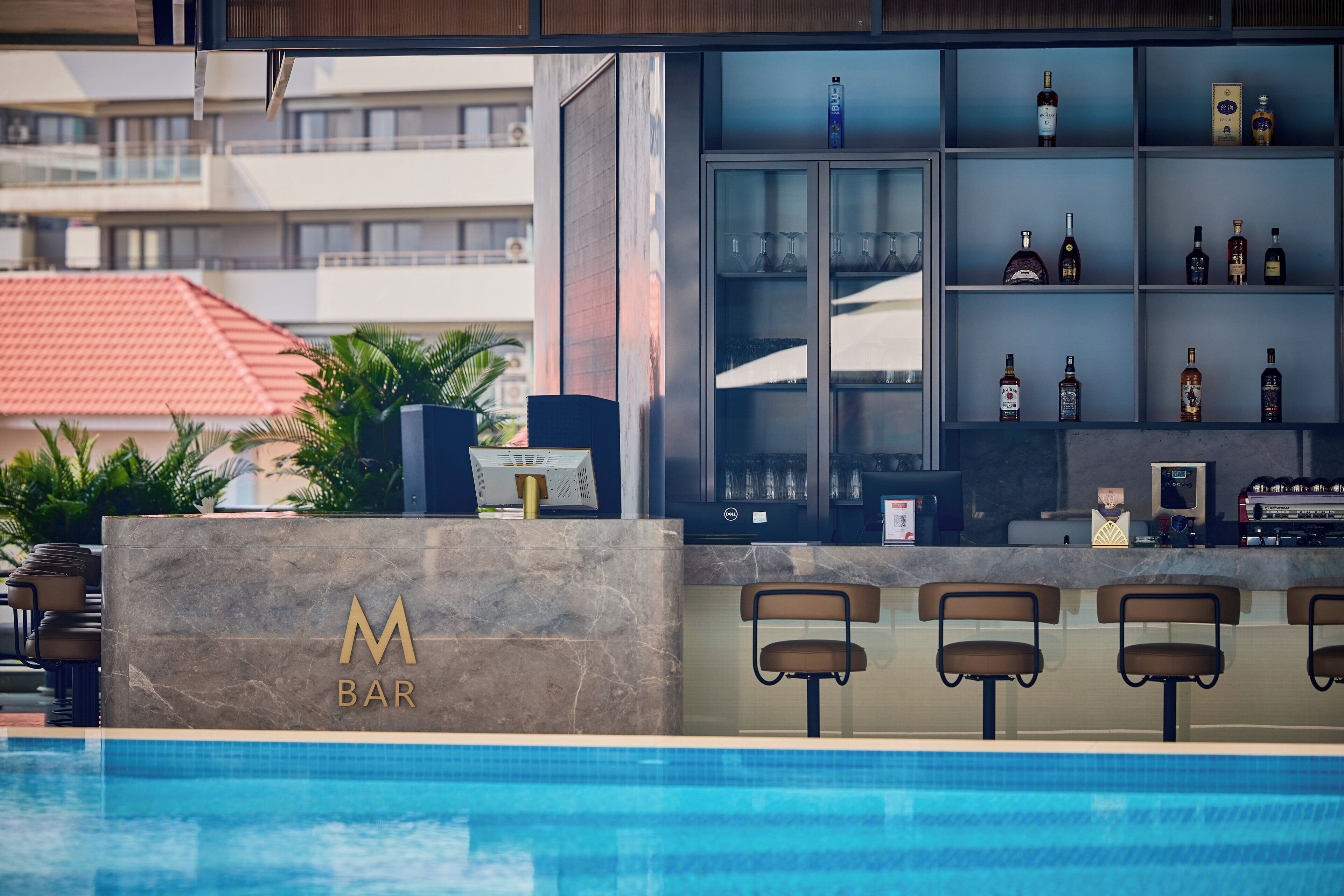 A bar area with a pool, bar stools, and shelves with bottles.