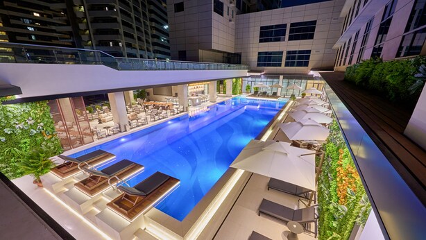 Un espace piscine aménagé sur le toit, avec des chaises longues, des parasols et un bar.