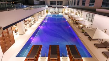 Una piscina al aire libre, sillones reclinables de piscina