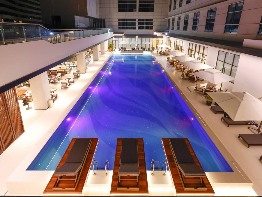 A large indoor swimming pool with multiple lounge areas and seating around the perimeter.
