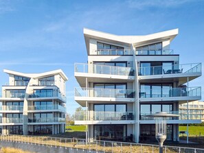 Een modern meerhooggezinsgebouw met balkons, grote ramen en een plat dak.