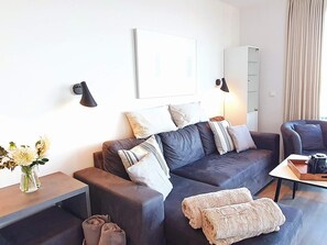 Een moderne woonkamer met een donkerbank, een salontafel en een lamp.