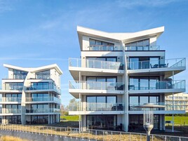 Un edificio moderno de varios pisos con balcones, ventanas amplias y techo plano.
