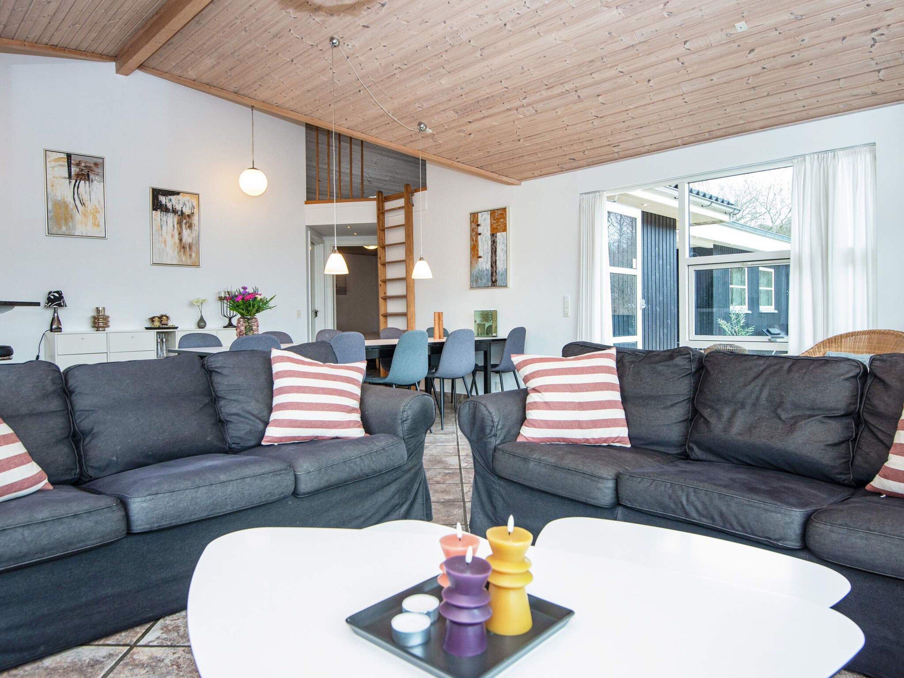 A modern living room with grey sofas, a white coffee table, and colorful candles.