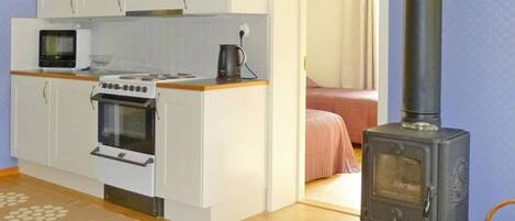 A compact kitchen with a stove, microwave, and cabinets.