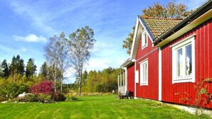 Ett rött hus med en välskött gräsmatta och träd i bakgrunden.