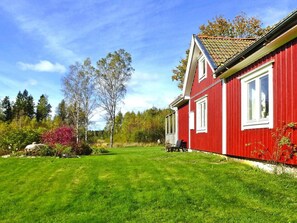 A red house with a well-maintained lawn and trees in the background. - 4 Person Holiday Home in Bralanda (Bralanda)