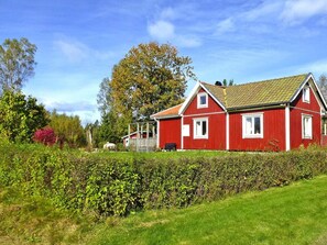 A red house with a sloped roof, surrounded by greenery and a hedge. - 4 Person Holiday Home in Bralanda (Bralanda)