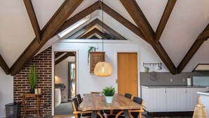 A dining area with a wooden table and chairs, a hanging light fixture, and a brick wall. - 6 Person Holiday Home in Ebeltoft (Ebeltoft)
