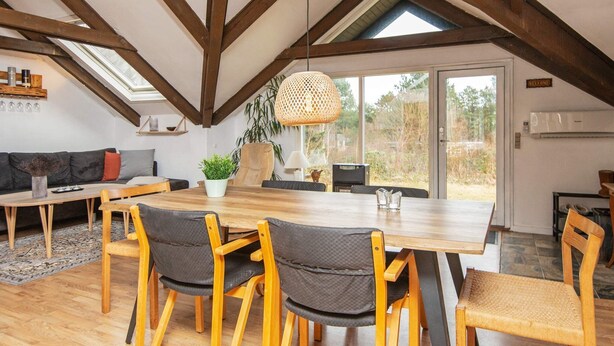 A dining area with a wooden table, four chairs, and a hanging light fixture. - 6 Person Holiday Home in Ebeltoft (Ebeltoft)