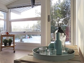 A room with a large window, a wooden table with decorative items, and a view of a snowy landscape. - 4 Star Holiday Home in Hals (Hals)