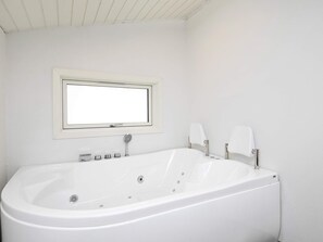 A modern bathroom with a freestanding bathtub, a window above the sink, and a showerhead. - 4 Star Holiday Home in Hals (Hals)