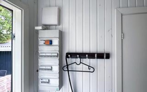 Une pièce avec un mur blanc, une porte, une fenêtre et un porte-manteau.