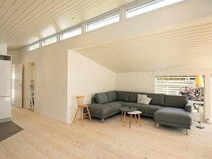 A modern living room with a grey sectional sofa, a wooden chair, and a small round table.