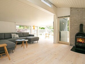 A modern living room with a sectional sofa, a small round table, and a fireplace. - 4 Star Holiday Home in Hals (Hals)