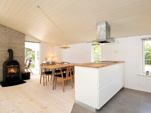 Une cuisine moderne dotée d’un îlot central, de chaises en bois, d’une cuisinière encastrée et d’une fenêtre donnant sur un espace verdoyant.