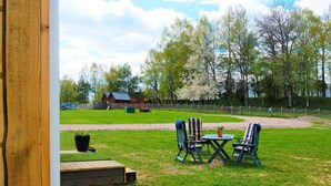 A grassy outdoor area with a wooden deck, a table, and two chairs. - 4 Star Holiday Home in Sandhem (Sandhem)