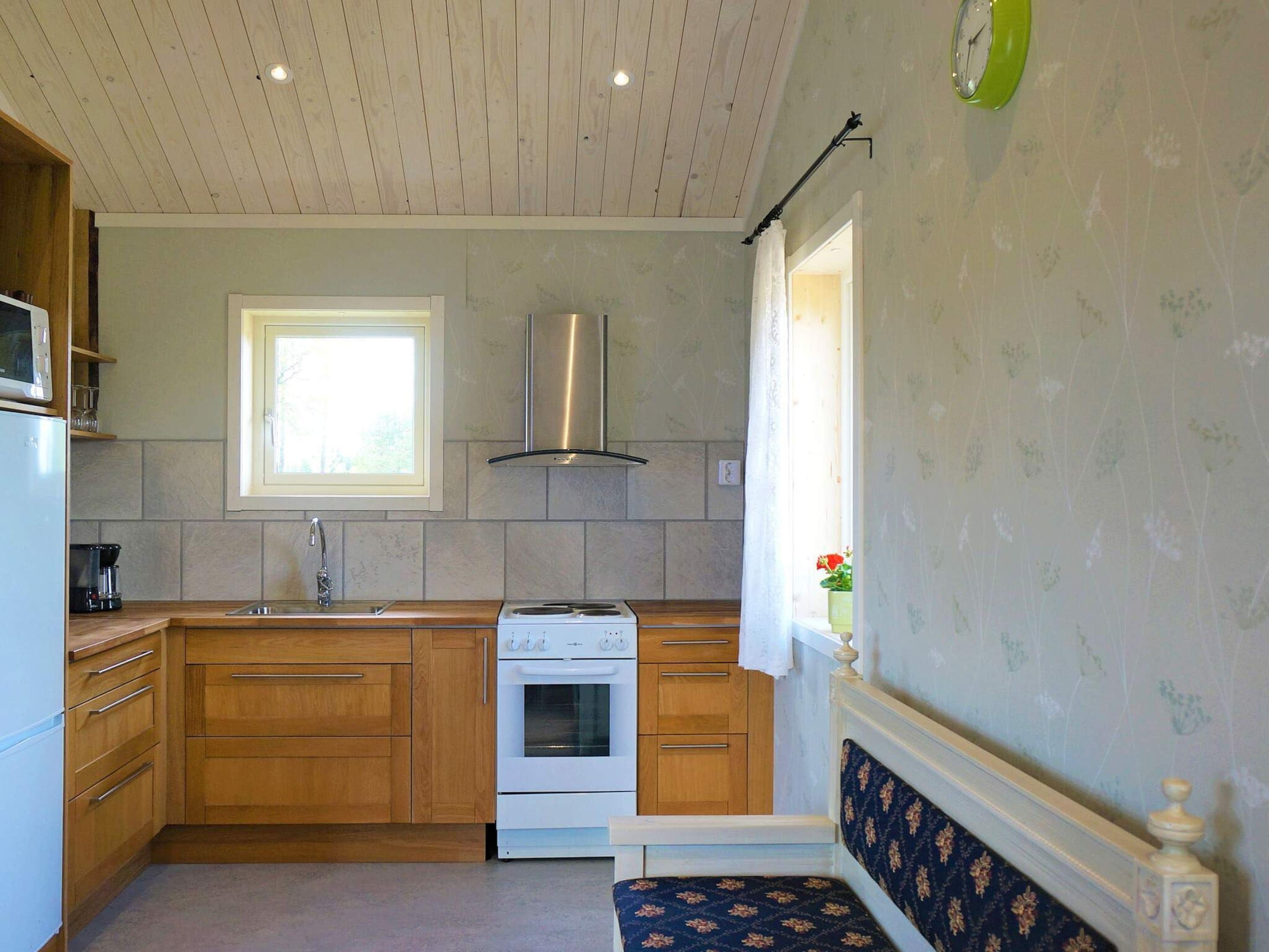 A compact kitchen with wooden cabinets, a built-in oven, and a window providing natural light.