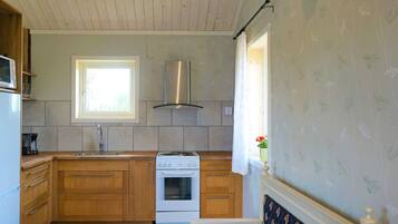 A compact kitchen with wooden cabinets, a built-in oven, and a window providing natural light.
