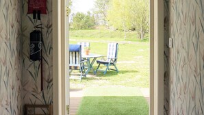 A doorway leading to an outdoor seating area with a table and chairs, a small rug, and a wooden bench. - 4 Star Holiday Home in Sandhem (Sandhem)