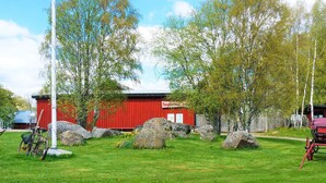 A red barn with a sign, surrounded by large rocks and trees. - 4 Star Holiday Home in Sandhem (Sandhem)