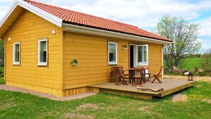 A yellow wooden house with a red-tiled roof, a covered patio with wooden furniture, and a grassy yard. - 4 Star Holiday Home in Sandhem (Sandhem)