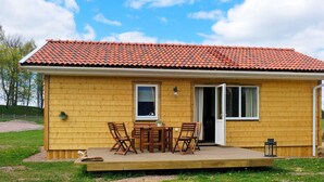 A wooden house with a tiled roof, a porch with wooden furniture, and a door leading to the interior. - 4 Star Holiday Home in Sandhem (Sandhem)