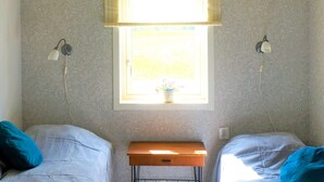 A room with two beds, a window with blinds, two wall-mounted lamps, and a small wooden table. - 4 Star Holiday Home in Sandhem (Sandhem)
