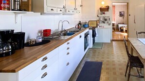 A compact kitchen with white cabinets, a wooden countertop, and a sink. There are various kitchen items and a small dining area visible. - 8 Person Holiday Home in Lycksele-by Traum (Kattisavan)