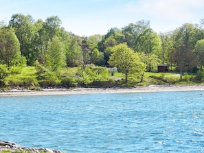 A lakeside view with a small cabin and lush greenery. - 9 Person Holiday Home in Fiskebackskil (Fiskebackskil)