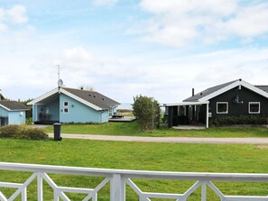 A residential area with two houses, one light blue and one dark blue, with a grassy yard and a white fence in the foreground. - 4 Star Holiday Home in Hadsund (Hadsund)