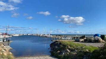 A marina with boats docked, a clear sky, and a calm waterway.
