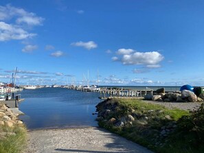 A marina with boats docked, a clear sky, and a calm waterway.
