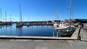 A marina with boats docked, a clear sky, and a building with a red roof in the background.