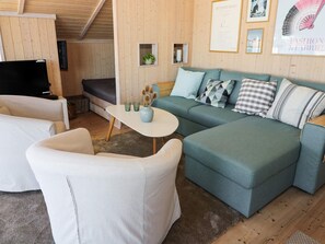 A cozy living room with a sectional sofa, a white armchair, and a small table with decorative items.