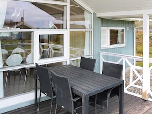 A covered outdoor area with a table and chairs, large windows, and a light blue building. - 4 Star Holiday Home in Hadsund (Hadsund)