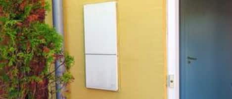 A yellow wall with a whiteboard, a door, and a plant.