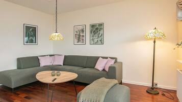 Una sala de estar con un sofá verde, una mesa de centro redonda y una lámpara de pie.