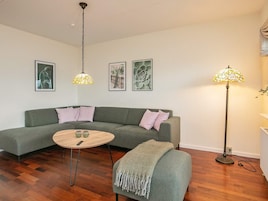 Una sala de estar con un sofá verde, una mesa de centro redonda y una lámpara de pie.