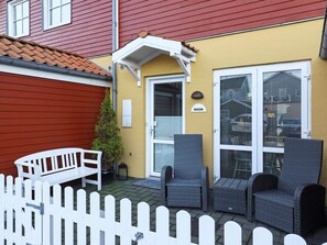 A patio with wicker furniture, a white picket fence, and a yellow building with a red roof. - 4 Star Holiday Home in Hals (Hals)