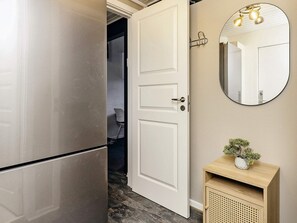 A modern kitchen with a stainless steel refrigerator, a white door, and a round mirror with lights above it. - 4 Star Holiday Home in Vaeggerlose (Vaeggerlose)