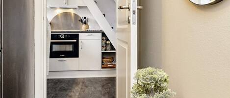 A compact kitchen with white cabinets, a Bosch oven, and a small potted plant on a wooden table.