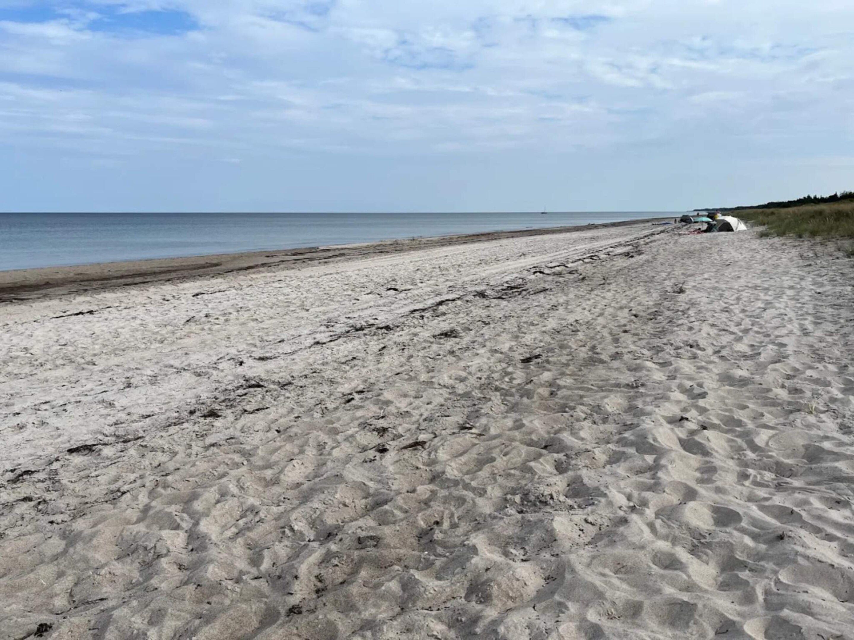 A sandy beach with a vehicle parked on the right side.