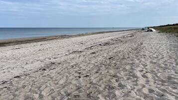 A sandy beach with a vehicle parked on the right side.
