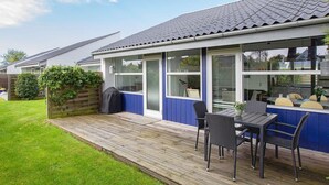 A residential property with a covered patio, a dining area with chairs, and a view of the adjacent house. - 4 Star Holiday Home in Vaeggerlose (Vaeggerlose)