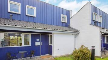A two-story building with a blue exterior and white trim. There are two windows on the upper floor and a door on the ground floor.