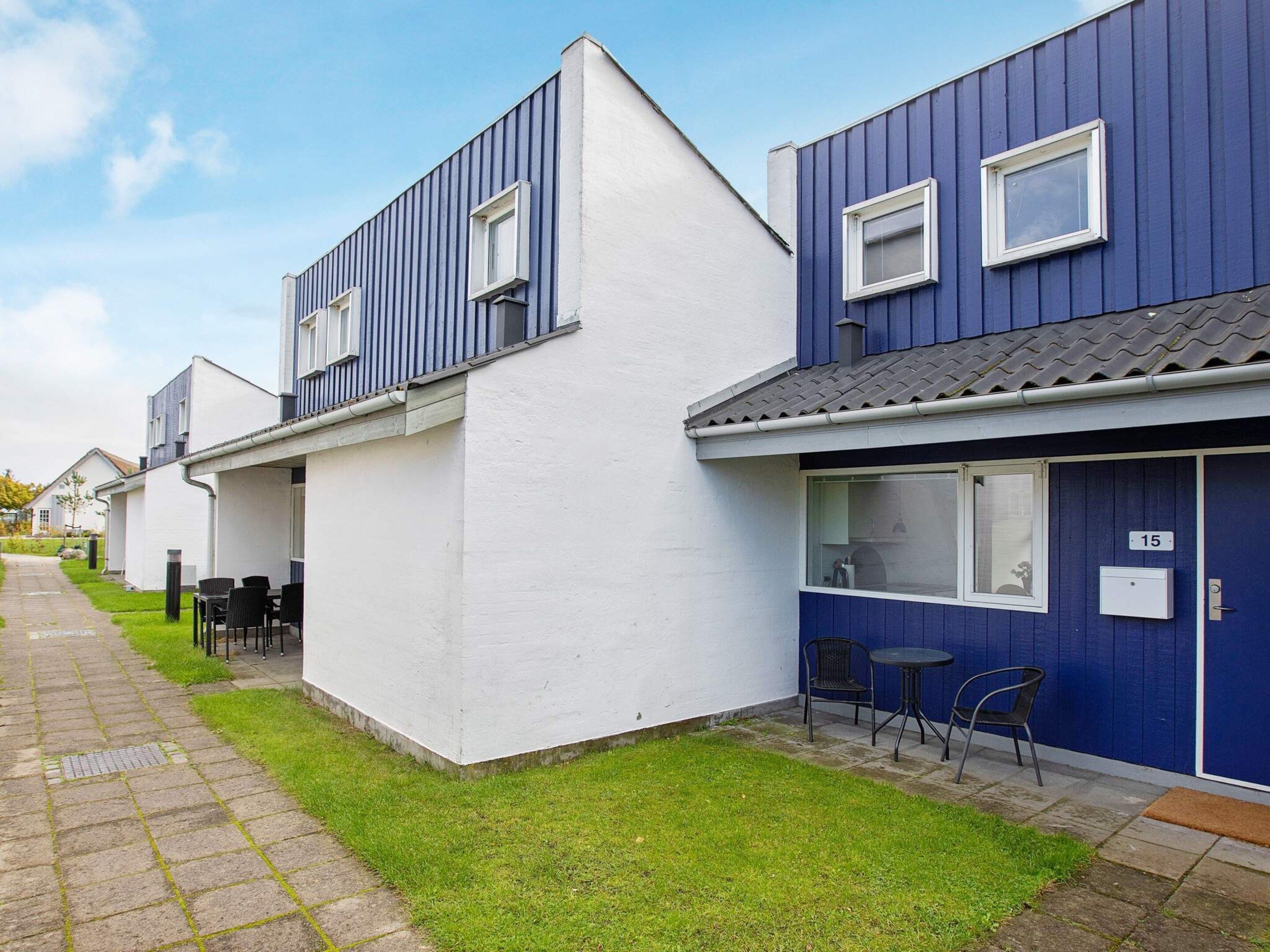 Een rij moderne, twee verdiepingen tellende gebouwen met een plat dak, een verhard voetpad en een klein gazon.