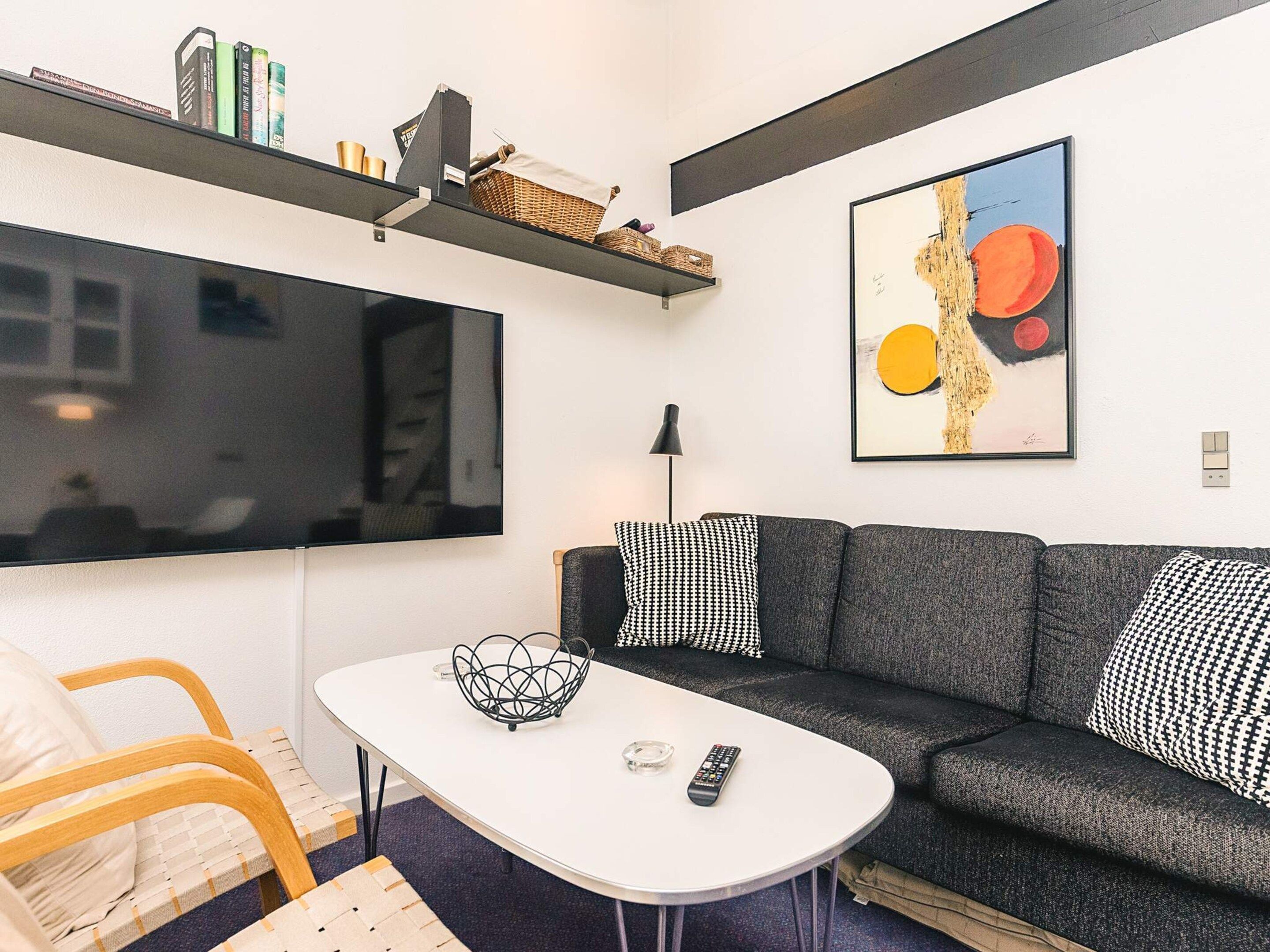 A modern living room with a grey sofa, a white coffee table, and a large window.