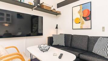 A modern living room with a grey sofa, a white coffee table, and a large window.